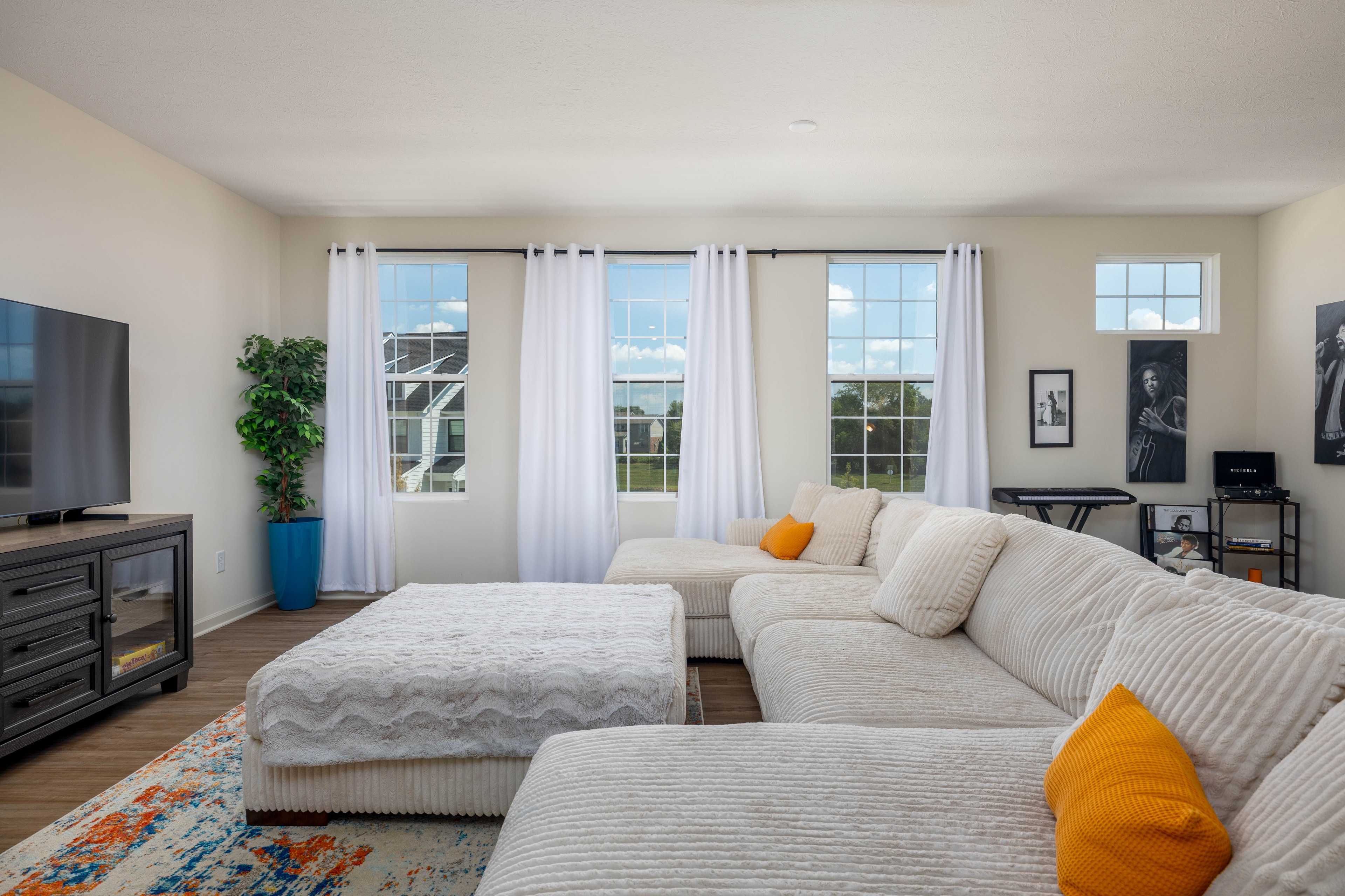 Staged residential living room with large windows and sectional sofa