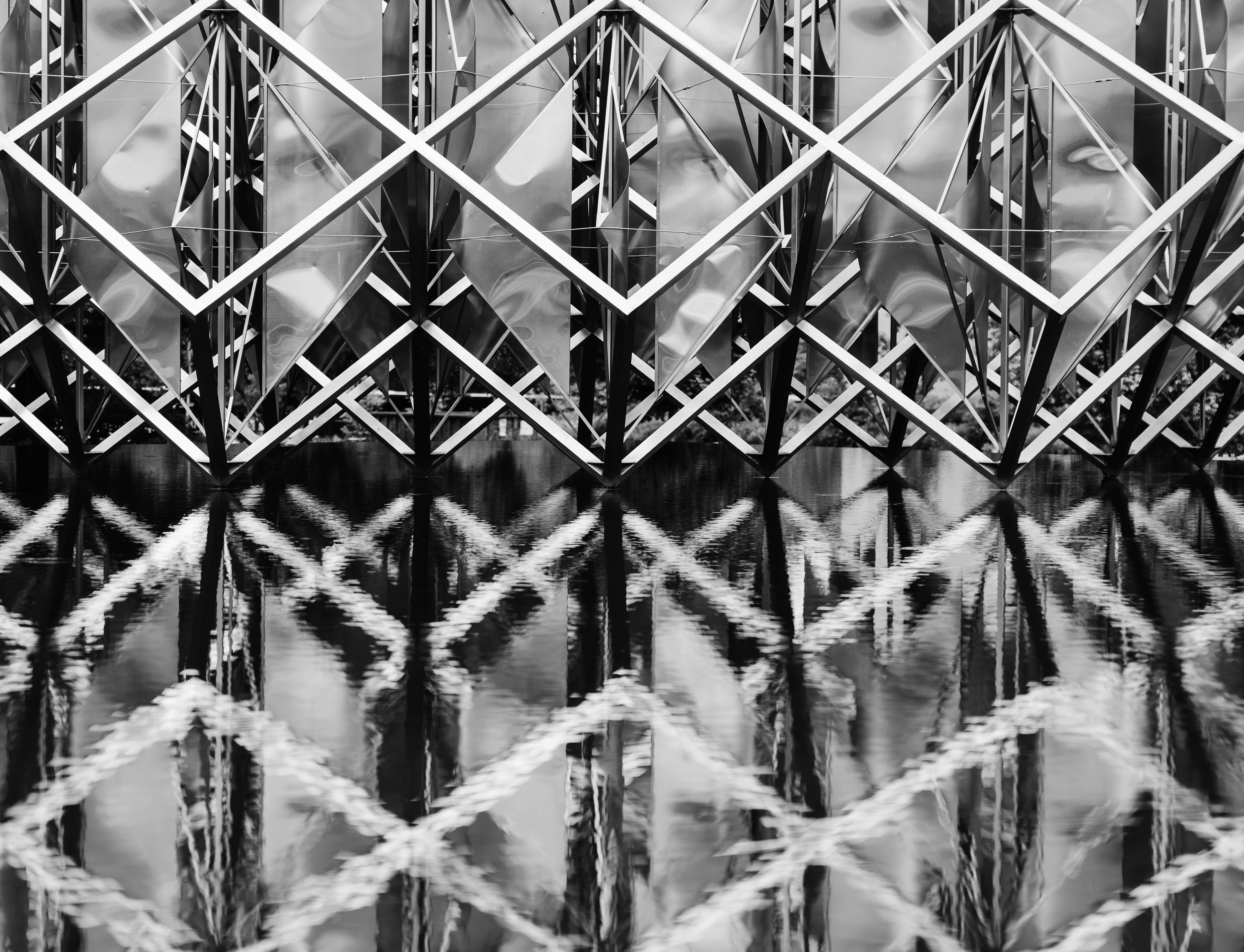 Black-and-white abstract architectural installation reflected in water